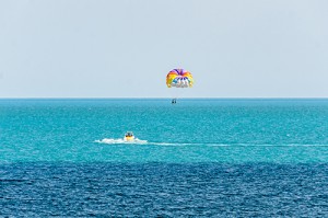 Colored parasail wing pulled by a boat in the sea water, Parasailing also known as parascending or parakiting.